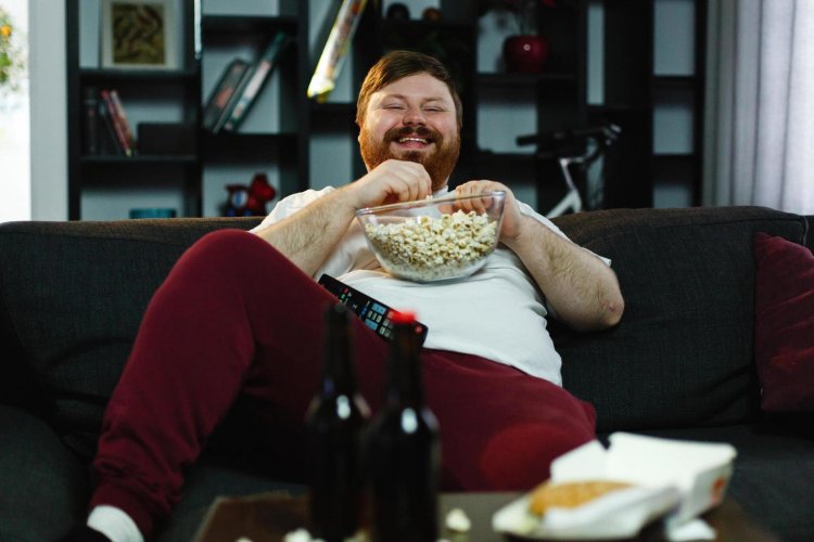 laughing-fat-man-sits-on-the-sofa-eating-popcorn-and-watching-tv-free-photo.jpg